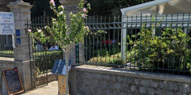 Ulaz u smještaj u Dubrovniku, s kamenim stubovima, metalnom ogradom i natpisom „Apartment Sobe Rooms“.