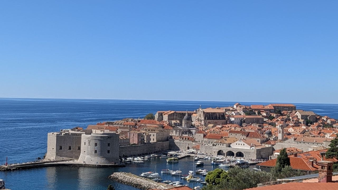 Panorama dubrovačkog starog grada, gradskih zidina i luke s brodicama.