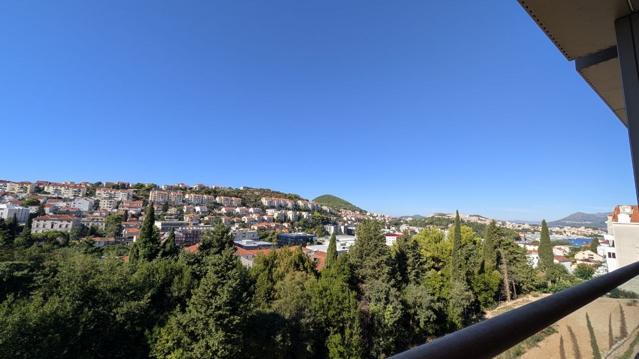 Pogled s balkona na dubrovačke kuće, zelenilo i more.