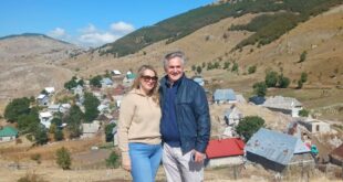 Supružnici stoje iznad planinskog sela s kućama i obroncima u pozadini