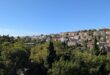 Panorama Dubrovnika s crvenim krovovima i zelenilom u sunčanom danu.