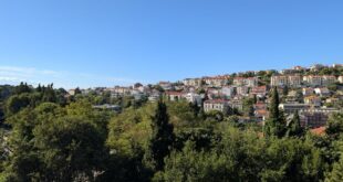 Panorama Dubrovnika s crvenim krovovima i zelenilom u sunčanom danu.