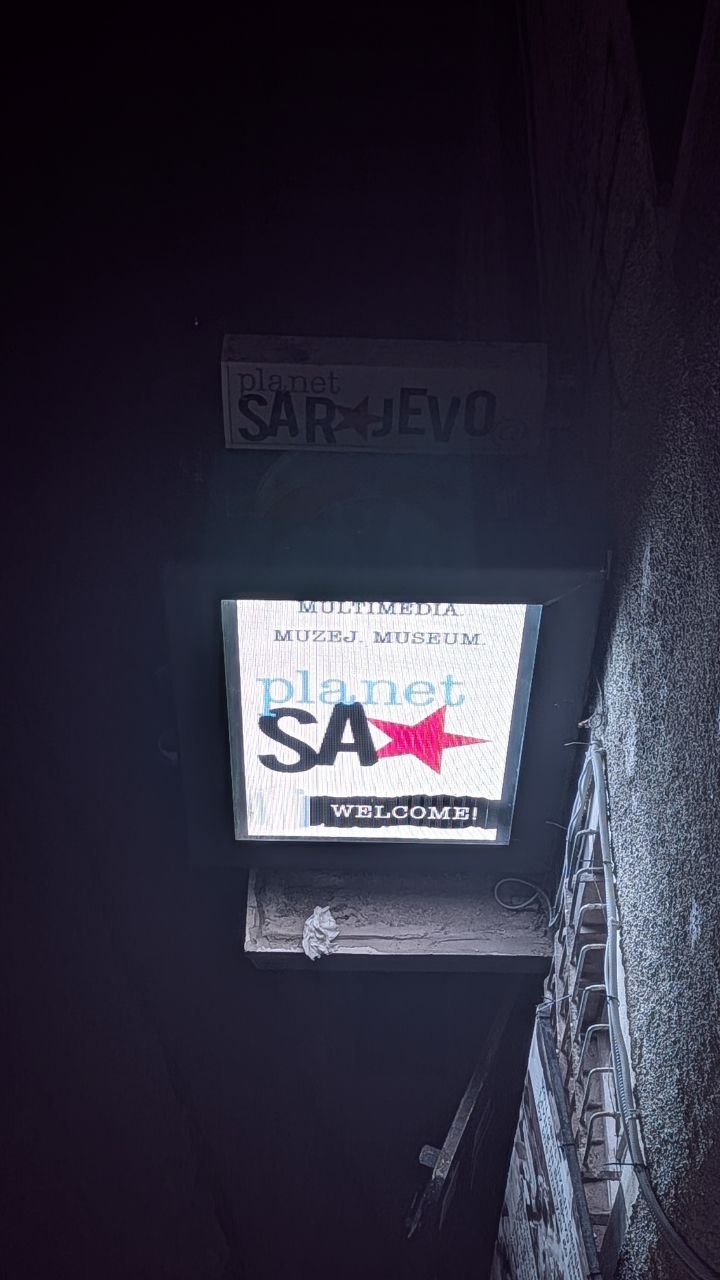 Osvijetljeni natpis Planet Sarajevo Multimedia Museum u uskom prolazu