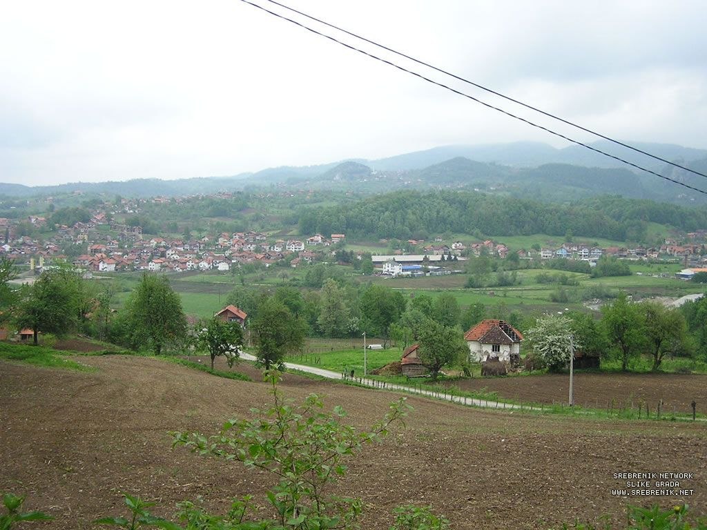 Panoramski pogled na njive, naselje i brda u okolini Srebrenika.