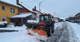 Traktor s ralicom čisti snijeg na ulici tokom zimskih uslova.