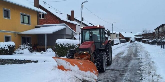 Traktor s ralicom čisti snijeg na ulici tokom zimskih uslova.