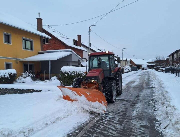 Traktor s ralicom čisti snijeg na ulici tokom zimskih uslova.